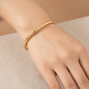 Pulsera dorada fina y abierta, diseño de brazalete mitad liso y mitad con relieve trenzado y acabado brillante