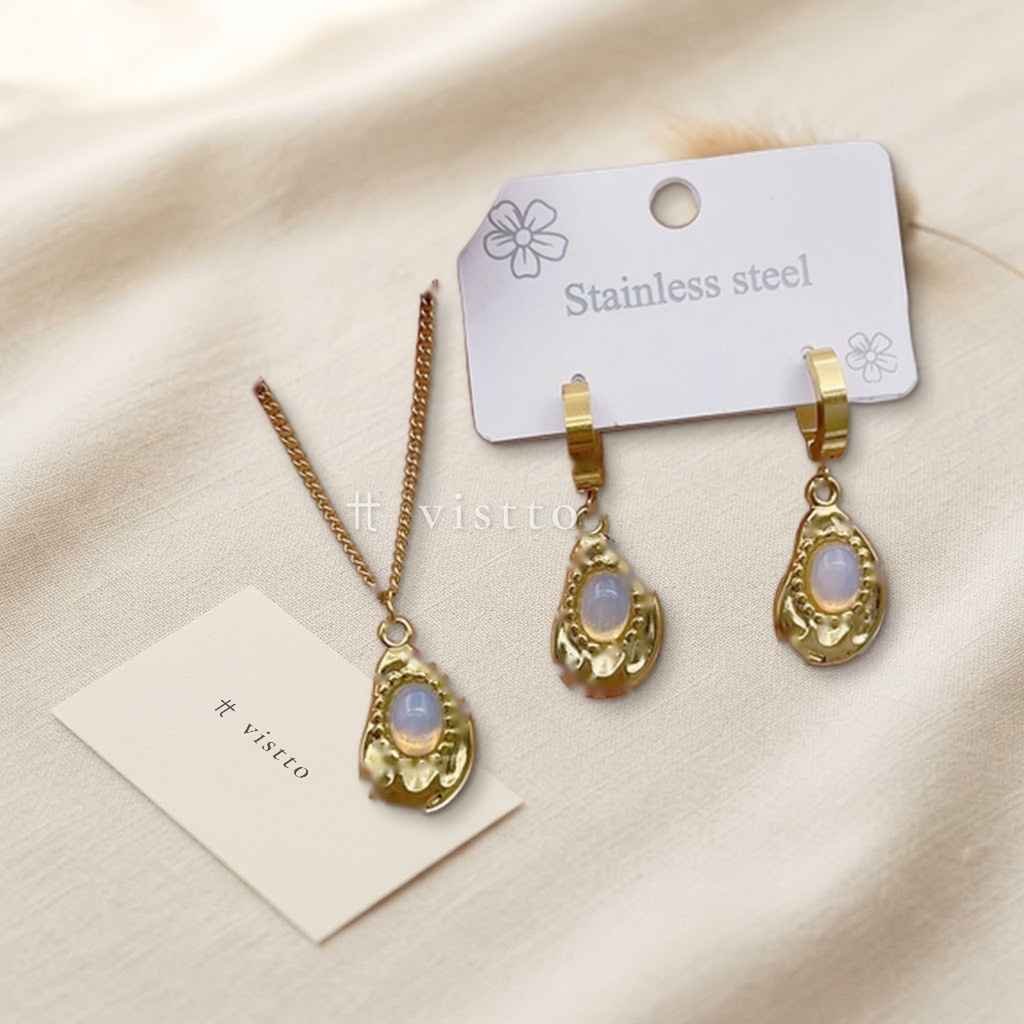 Set de collar y zarcillos dorados, diseño de colgantes en forma de gota con piedra ovalada blanca lechosa y borde texturizado