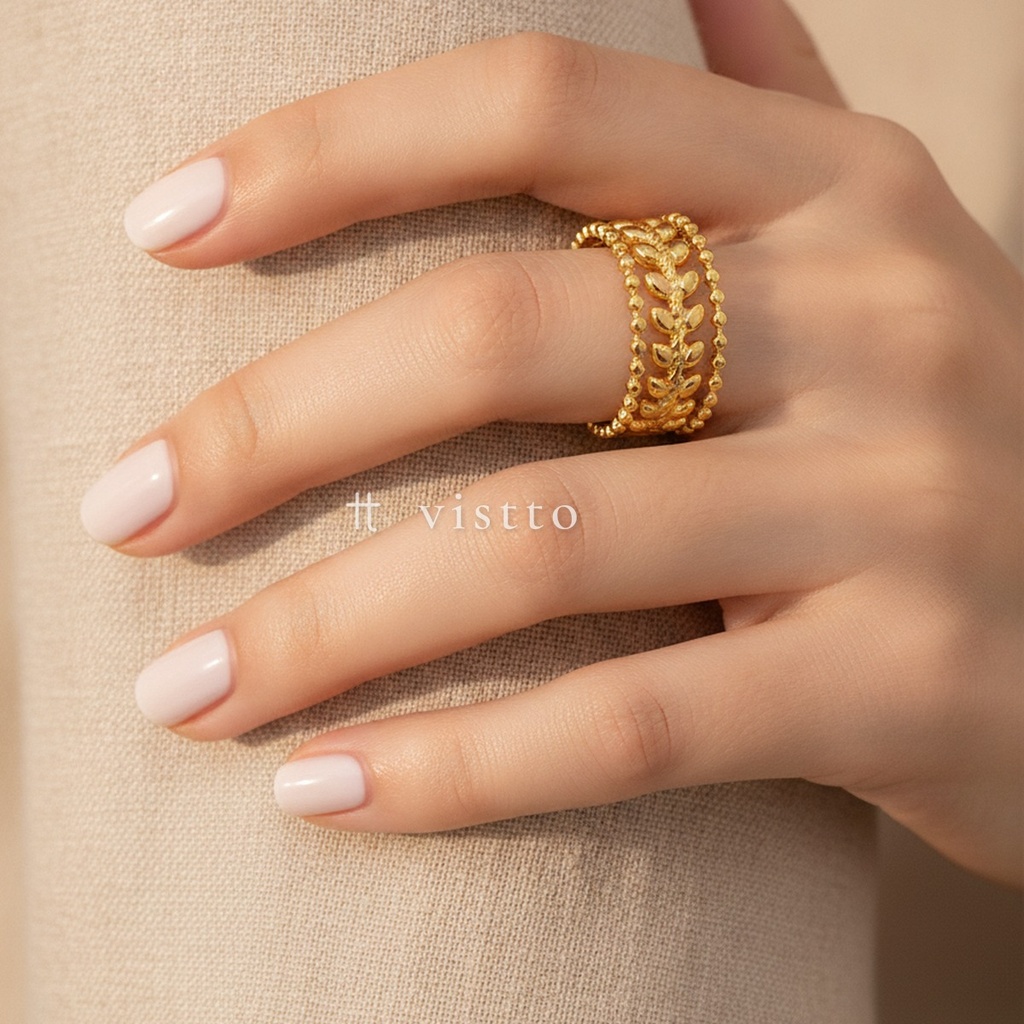 Anillo dorado ancho y abierto, diseño de banda calada con hojas y bordes de pequeñas esferas, acabado brillante