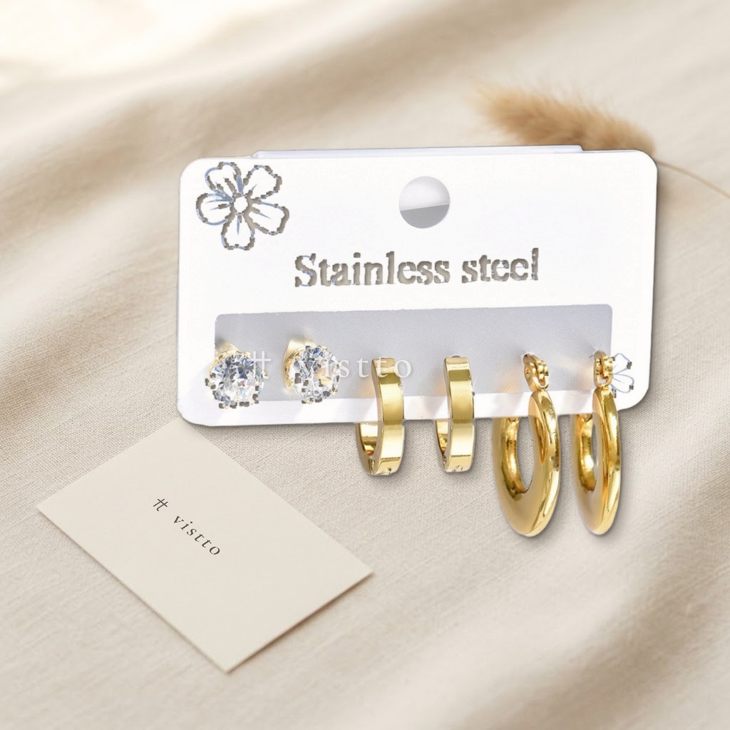 Set de tres pares de zarcillos dorados, con botón de circonia cúbica transparente, huggie liso y argolla gruesa de tubo liso