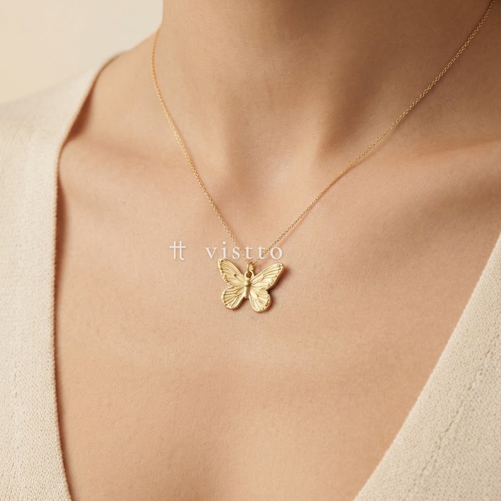 Dije dorado de mariposa de alas abiertas con nervaduras grabadas en relieve y argolla superior