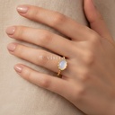 Anillo dorado fino, diseño de aro con esferas laterales y motivo frontal de piedra ovalada blanco lechoso