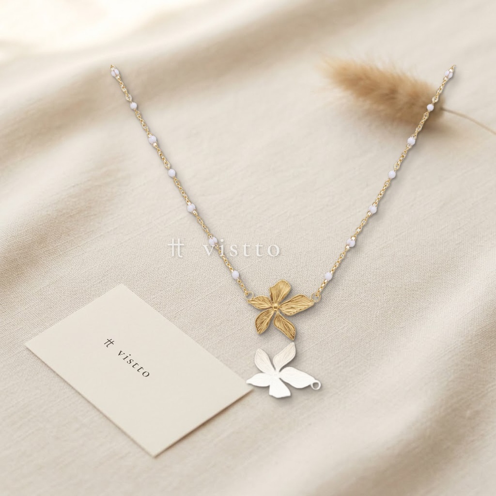 Collar dorado de cadena fina con puntos de esmalte blanco y flor central de cinco pétalos texturizados