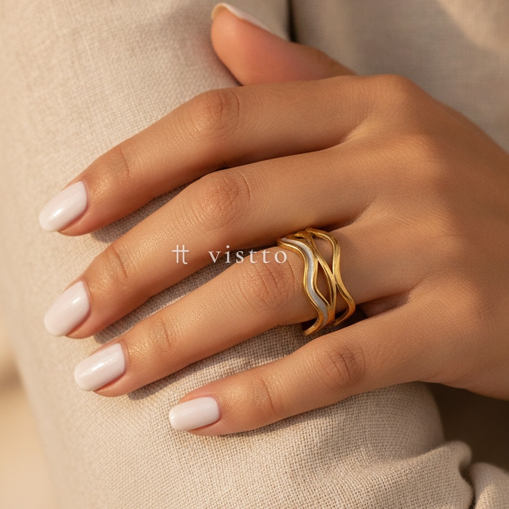 Anillo dorado y blanco ancho y abierto, diseño de bandas onduladas caladas con una banda central de esmalte blanco