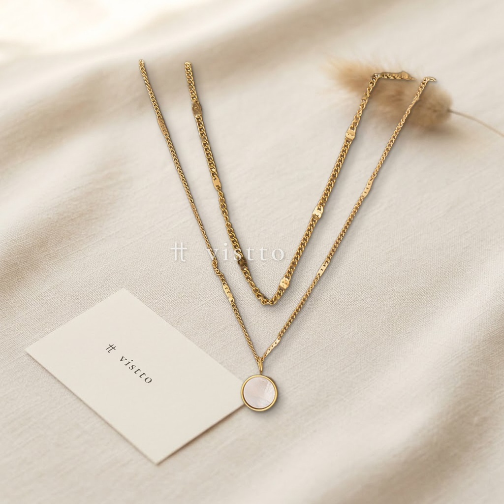 Collar dorado de doble cadena superpuesta con dije redondo de concha blanca