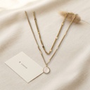 Collar dorado de doble cadena superpuesta con dije redondo de concha blanca