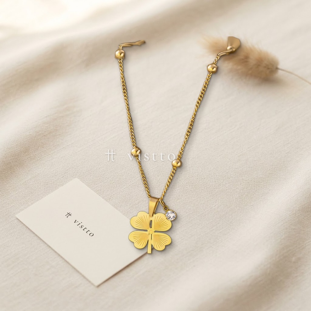 Collar dorado de cadena fina con bolitas, con dije de trébol de cuatro hojas calado y una circonia transparente colgante