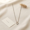 Collar dorado de cadena fina con dije de corazón de concha blanca enmarcado en borde de bolitas