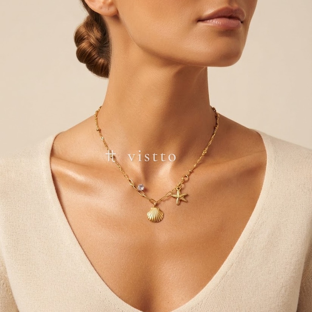 Collar dorado de cadena de eslabones mixtos con cuentas, con dijes de concha estriada y estrella de mar y una circonia transparente