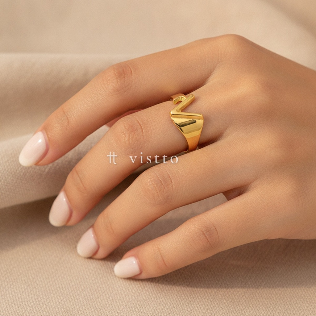 Anillo dorado ancho y abierto, diseño de banda lisa con motivo frontal de la letra A calada y acabado brillante