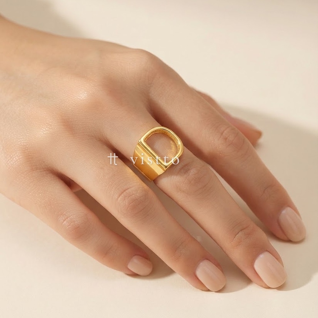 Anillo dorado ancho y abierto, diseño de banda lisa con motivo frontal de la letra D calada y acabado brillante