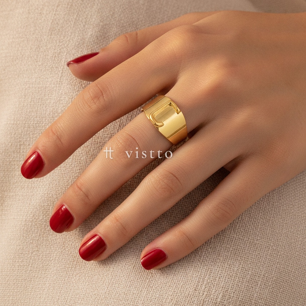 Anillo dorado ancho y abierto, diseño de banda lisa con motivo frontal de la letra J calada y acabado brillante