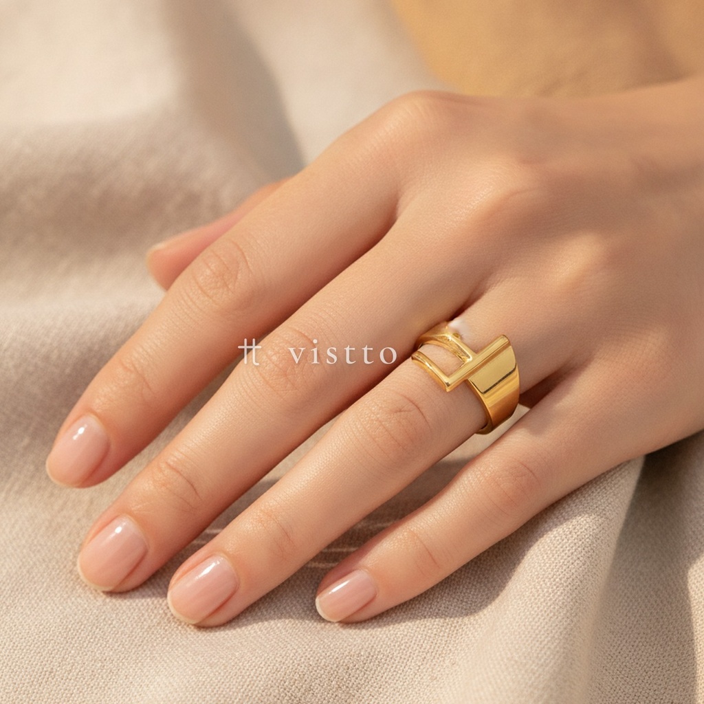 Anillo dorado ancho y abierto, diseño de banda lisa con motivo frontal de la letra F calada y acabado brillante