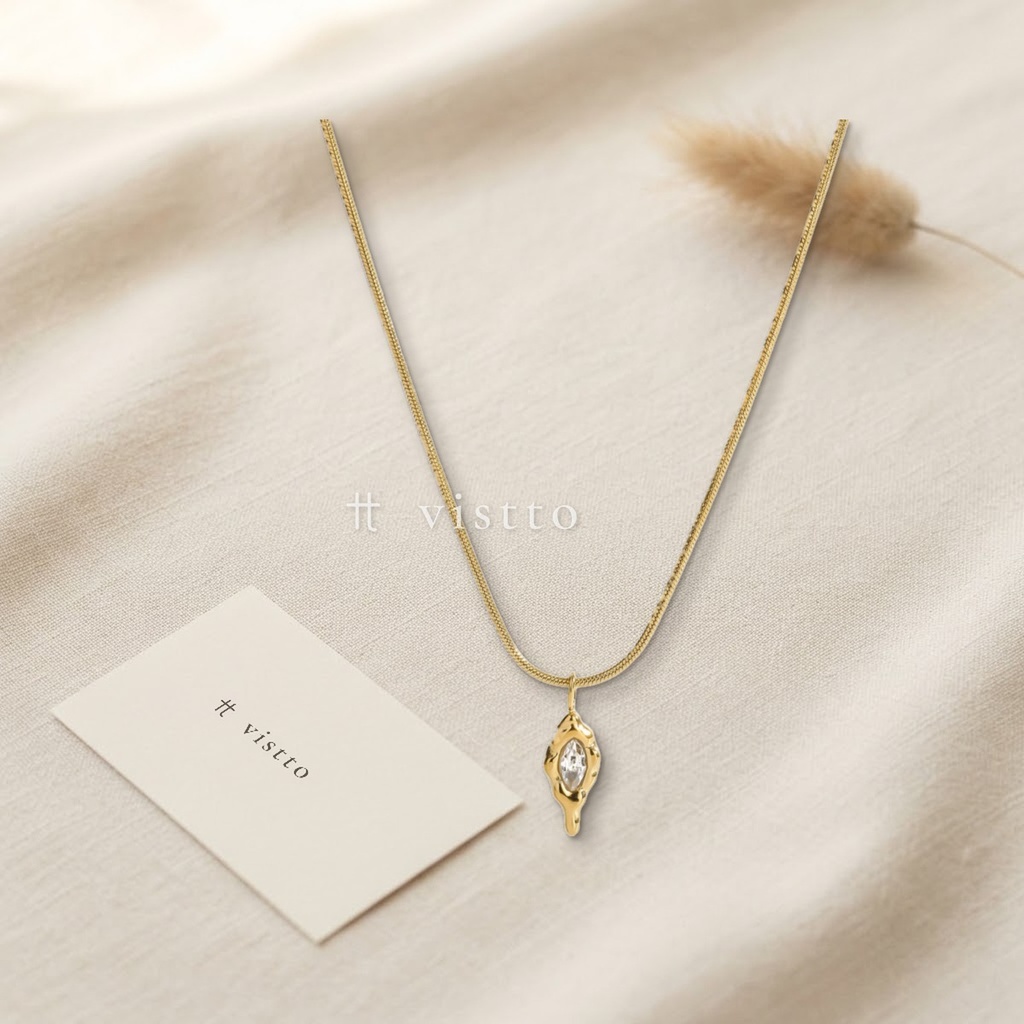 Collar dorado de cadena serpiente fina, con dije orgánico de bordes fundidos y una circonia transparente en talla marquesa
