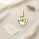 Dije dorado en forma de corazón con borde liso, una circonia transparente en talla corazón y anilla para colgar
