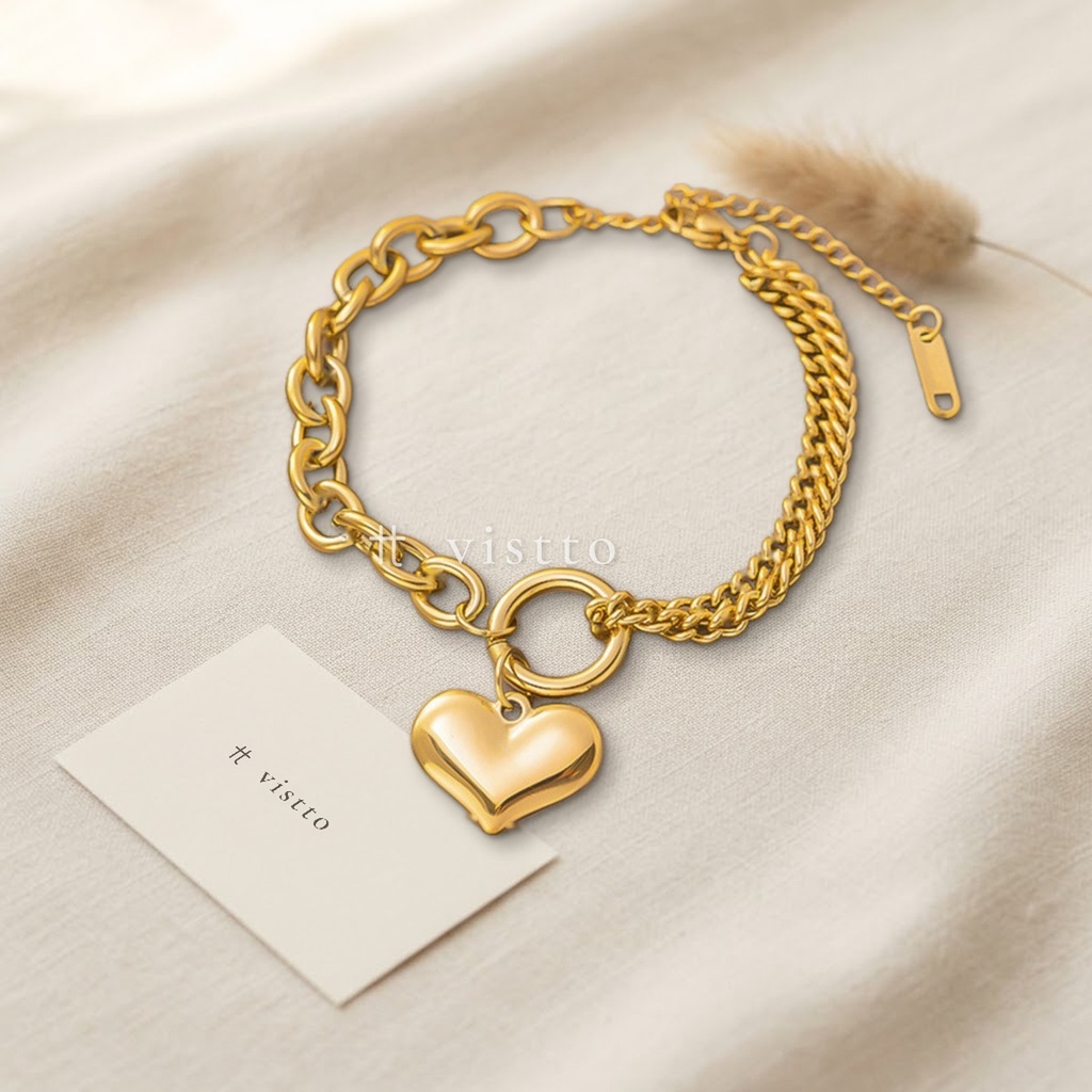 Pulsera dorada de grosor estándar, diseño asimétrico de eslabones redondos y cadena barbada con dije de corazón abombado